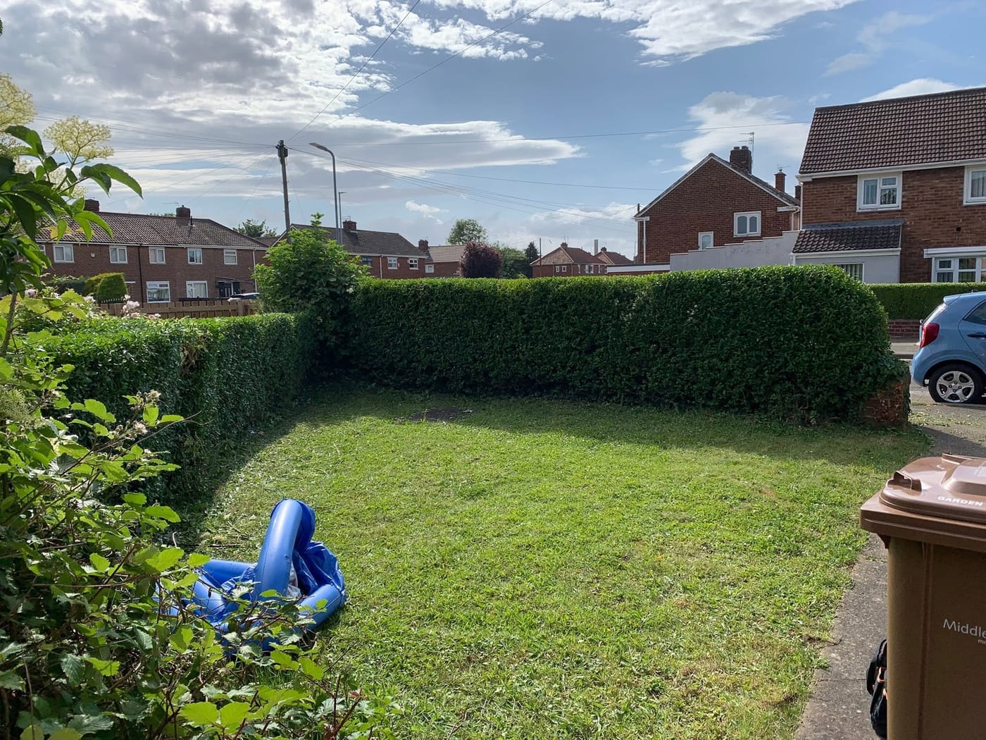 A long, neatly trimmed hedge around a freshly cut lawn in Park End